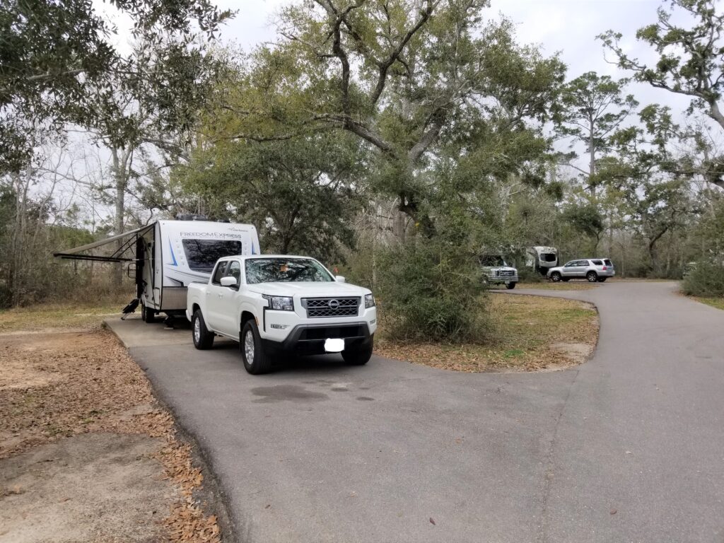 Truck and travel trailer parked on a paved pad in a the Buccaneer State Park campground