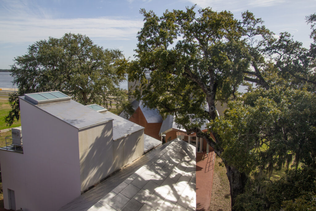 Museum buildings, live oak trees on the Ohr'O'Keefe Museum of Art campus with Gulf waters beyond as seen from the second floor of the main museum building