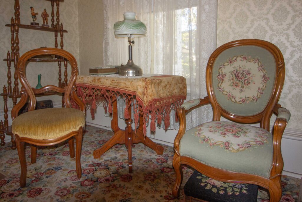 Two vintage chairs and a table. One chair has a needlepoint seat and back