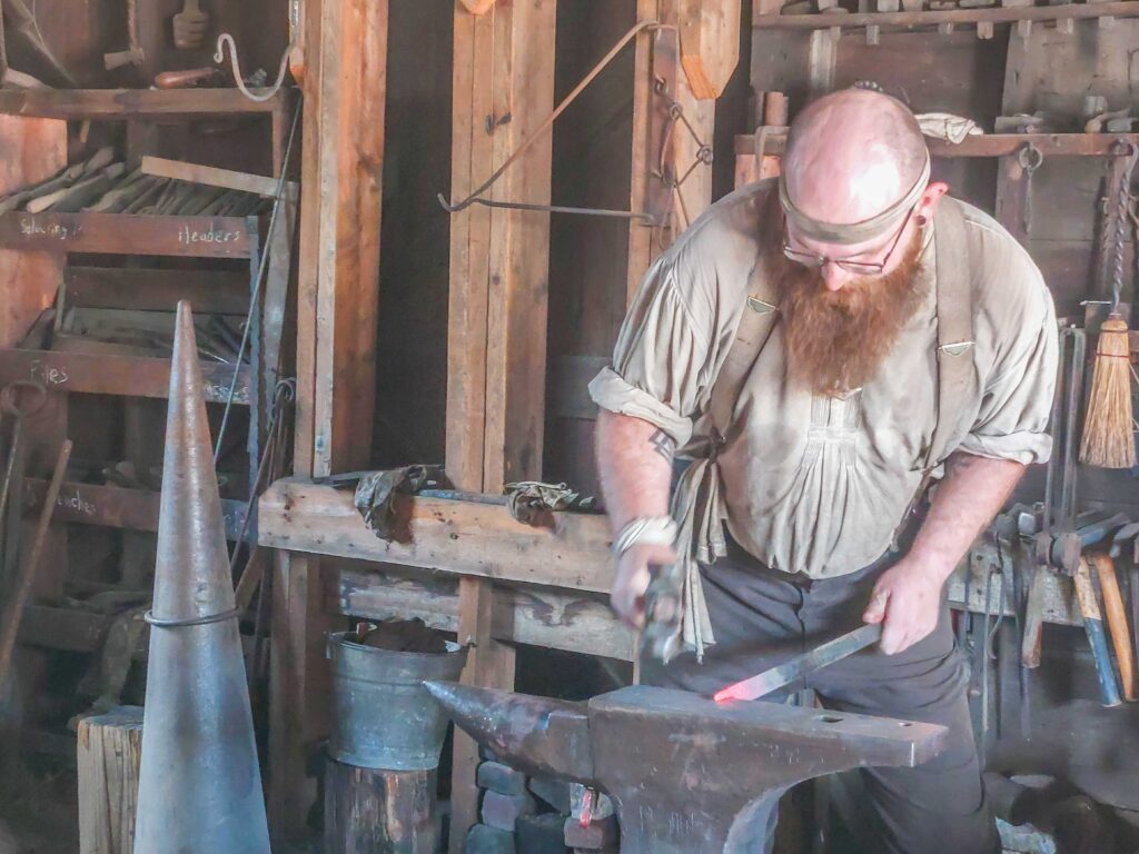 blacksmith hammering a red-hot steel rod on an anvil