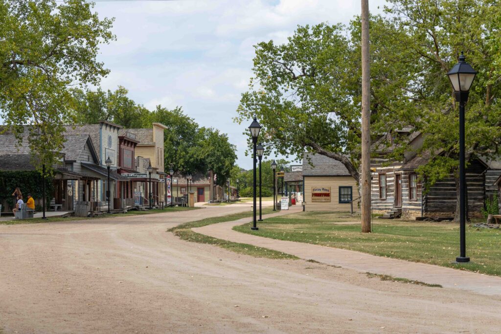 Dirt road lined with vintage-type streetlights and historical buildings