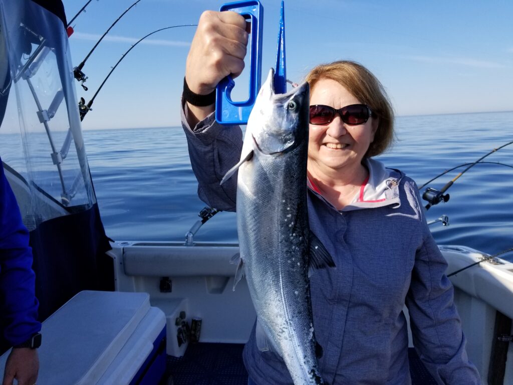 Author aboard a Kenosha Charter Boat holding a coho salmon she caught.